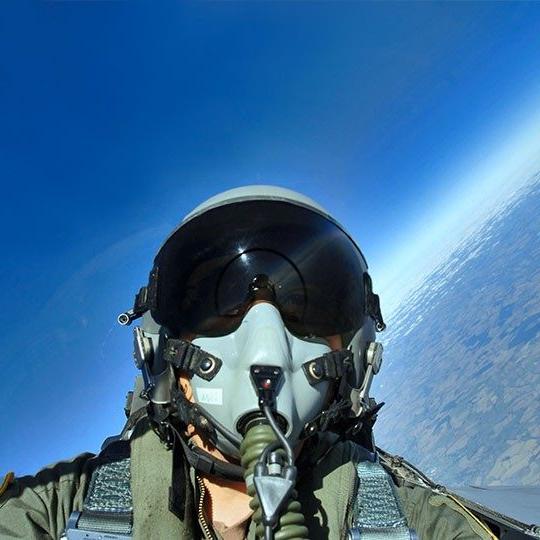 Fighter pilot looking out window of jet